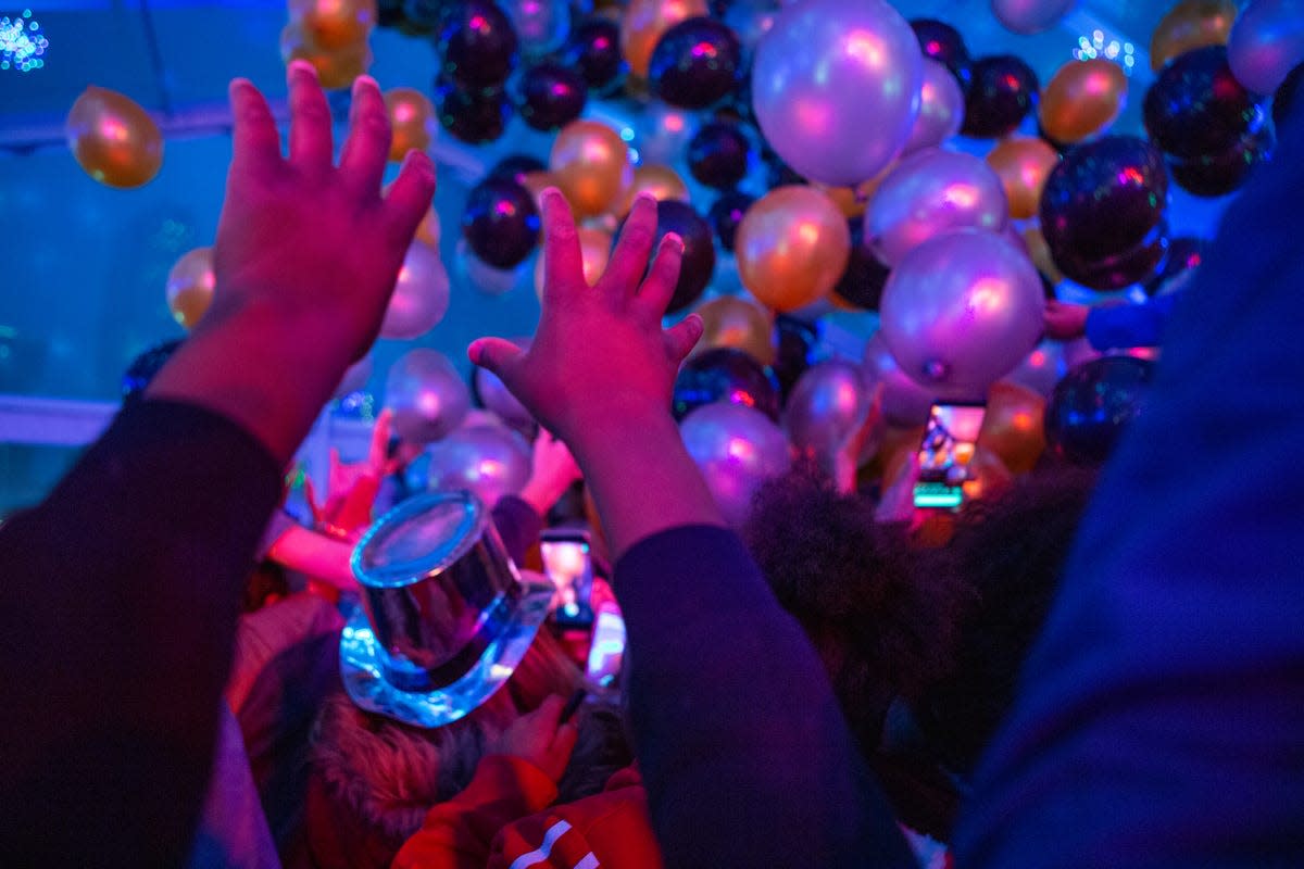 People reach for balloons during a New Year's Eve Balloon Drop at Beacon Park in Detroit, Tuesday, Dec. 31, 2019. Hundreds gathered to dance and have their face painted, leading up the balloon drop.
