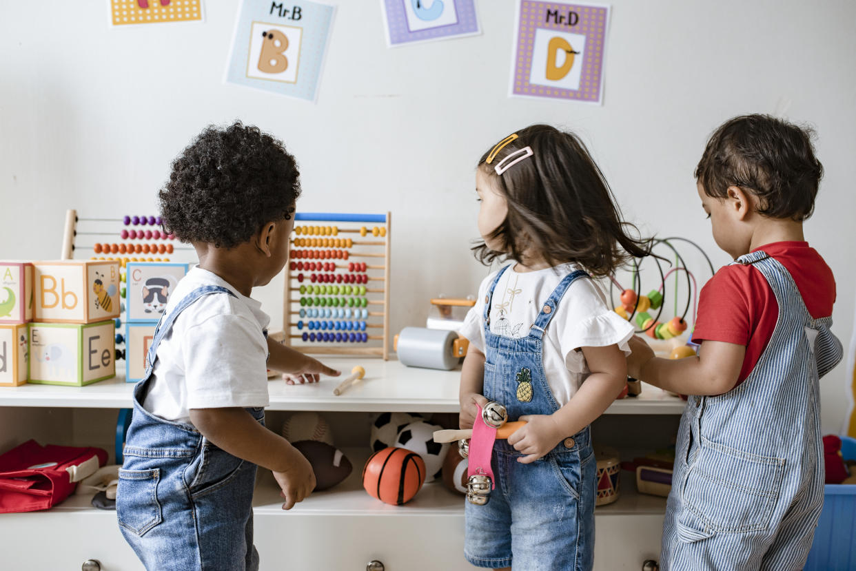 Three kids in overalls play games at preschool. Hand, foot and mouth disease primarily affects young children under the age of 5. 