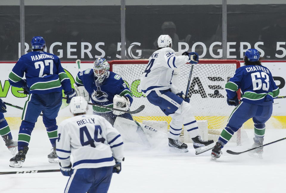 Toronto Maple Leafs' Auston Matthews (34) scores against Vancouver Canucks goalie Braden Holtby (49) as Travis Hamonic (27) and Jalen Chatfield (63) watch during the second period of an NHL hockey game in Vancouver, British Columbia, Sunday, April 18, 2021. (Darryl Dyck/The Canadian Press via AP)