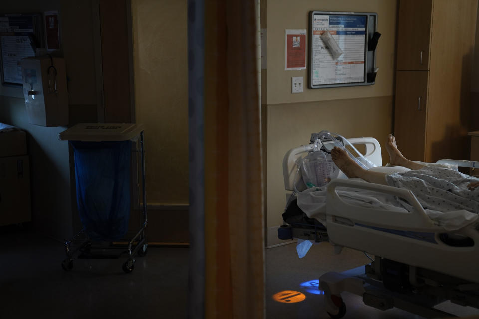 A body of a COVID-19 patient lies in a bed at Providence Holy Cross Medical Center in the Mission Hills section of Los Angeles on Saturday, Jan. 9, 2021. The patient died shortly after receiving the sacrament of anointing of the sick administered over the phone by a priest. (AP Photo/Jae C. Hong)