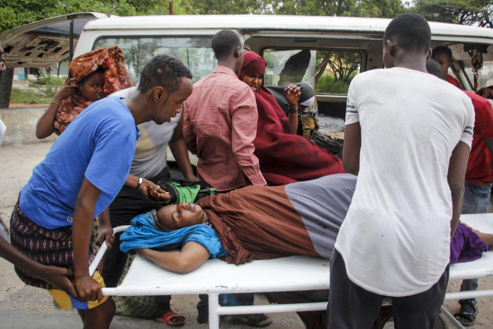 Medical workers and other Somalis help a civilian woman, who was wounded when a powerful car bomb blew off the security gates to the Elite Hotel, as she arrives at a hospital in Mogadishu, Somalia Sunday, Aug. 16, 2020. A Somali police officer says at least 10 people have been killed and more than a dozen others injured in an ongoing siege at the beachside hotel in Somalia's capital where security forces are battling Islamic extremist gunmen who have invaded the building. (AP Photo/Farah Abdi Warsameh)