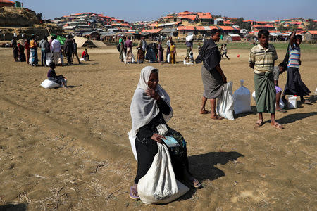 Rohingya refugees sit on the ground after collecting aid supplies in Thyingkhali refugee camp in Cox's Bazar, Bangladesh, January 21, 2018. REUTERS/Mohammad Ponir Hossain