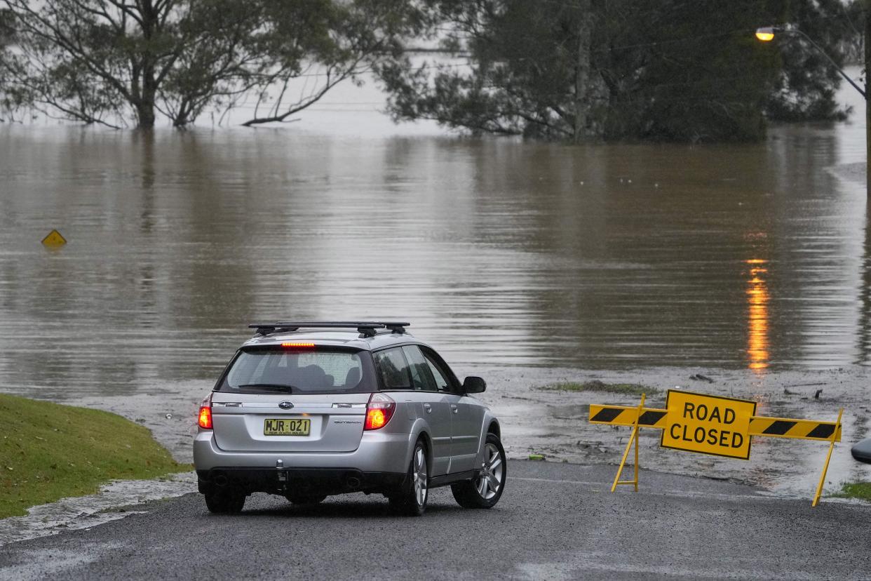 A car turns at a closed road in Richmond on the outskirts of Sydney, Australia, Monday, July 4, 2022.