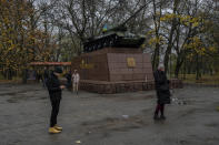 Residents talk on the phone next to a monument with a recently paint Ukrainian flag in Kherson, southern Ukraine, Sunday, Nov. 20, 2022. The Russian withdrawal from the only provincial capital it gained in nine months of war was one of Moscow most significant battlefield losses. Now that its troops hold a new front line, the Ukrainian military said through a spokesman, the army is planning its next move. (AP Photo/Bernat Armangue)