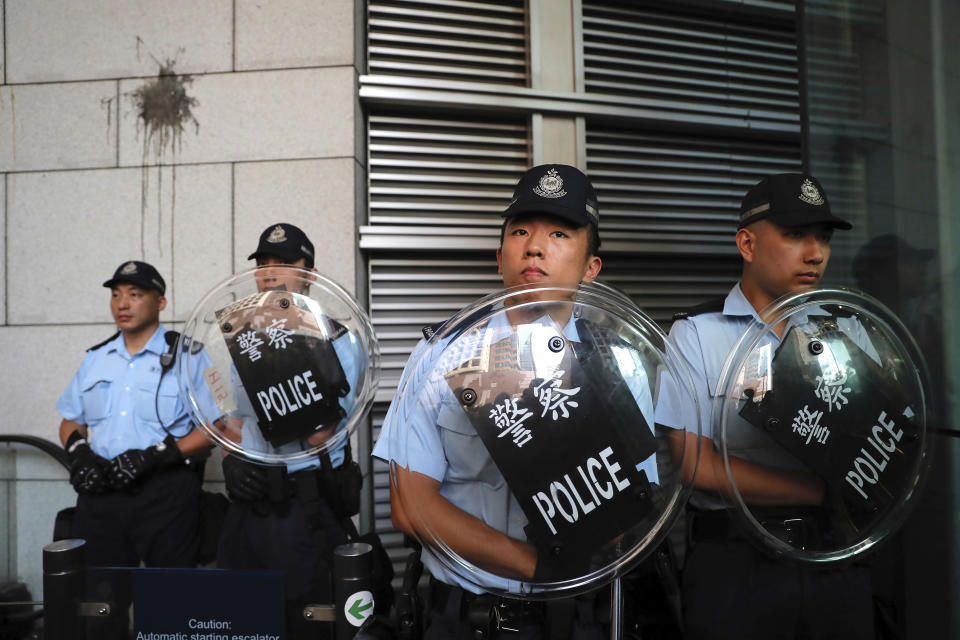 Police officers stand at the police headquarters as protestors gather outside in Hong Kong, Friday, June 21, 2019. More than 1,000 protesters blocked Hong Kong police headquarters into the evening Friday, while others took over major streets as the tumult over the city's future showed no signs of abating. The mark on the wall is from an egg thrown by protestors. (AP Photo/Kin Cheung)