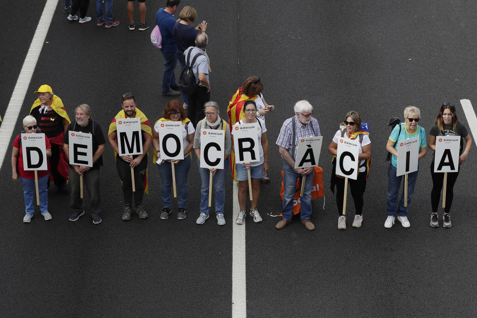 Protesters march with a letters reading 'Democracy' on the fifth day of protests over the conviction of a dozen Catalan independence leaders in Barcelona, Spain, Friday, Oct. 18, 2019. Various flights into and out of the region are cancelled Friday due to a general strike called by pro-independence unions and five marches of tens of thousands from inland towns are expected converge in Barcelona's center on Friday afternoon for a mass protest with students to and workers who are on strike. (AP Photo/Manu Fernandez)