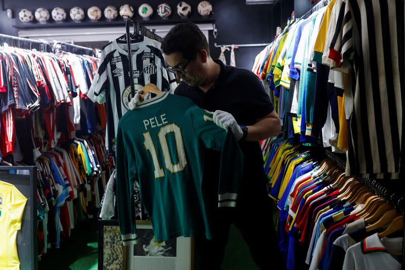 Cassio Brandao, de 41 años, sostiene una camiseta usada por Pelé en una habitación llena de percheros que en abril de 2024 lo convirtieron en poseedor del título Guinness World Records como propietario de la colección de camisetas de fútbol más grande del mundo, en Sao Paulo, Brasil