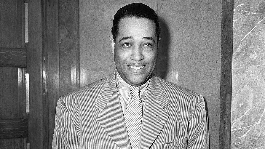 duke ellington smiling as he stands with his arms at his sides in a photo
