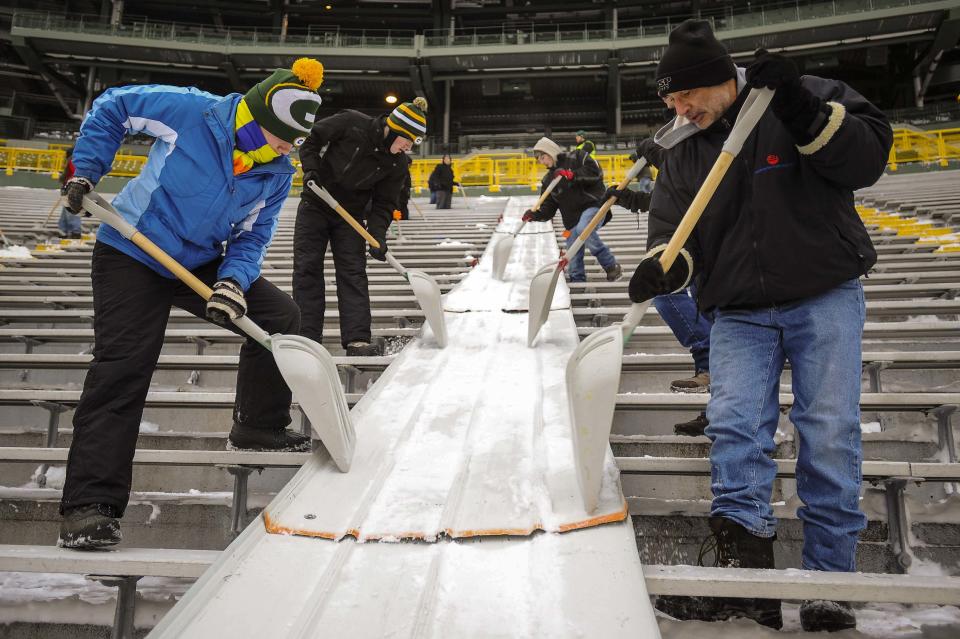 Paid volunteers clear snow from the bleachers at Lambeau Field in Green Bay, Wisconsin, the home field of the Green Bay Packers of the National Football League (NFL), December 21, 2013. In winter months, the team calls on the help of hundreds of citizens, who also get paid a $10 per-hour wage, to shovel snow and ice from the seating area ahead of games, local media reported. The Packers will host the Pittsburgh Steelers on Sunday, December 22. REUTERS/Mark Kauzlarich (UNITED STATES - Tags: ENVIRONMENT SPORT FOOTBALL)