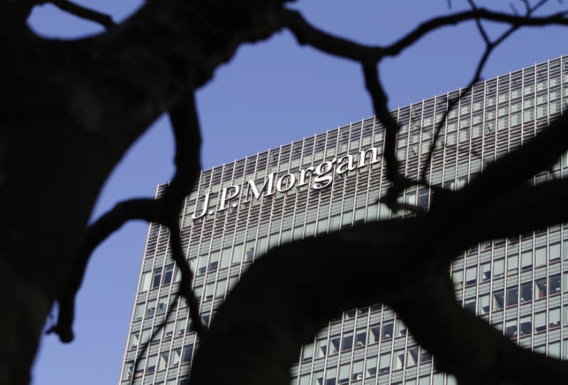 A sign on the Canary Wharf offices of JP Morgan is seen through the branches of a tree in London