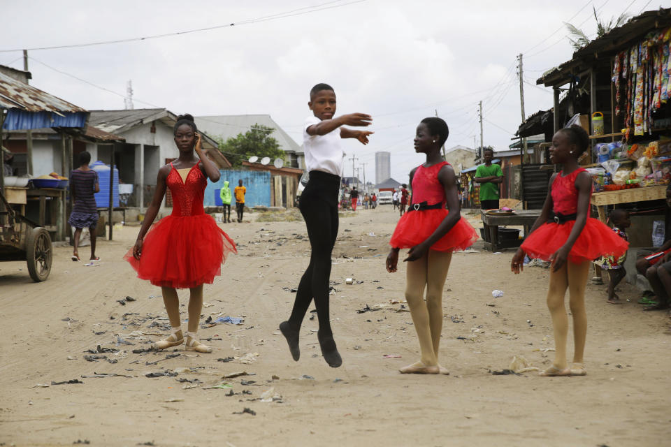 Ballet student Anthony Mmesoma Madu, center, dances in the street as fellow dancers look on in Lagos, Nigeria on Aug. 18, 2020. Cellphone video showing the 11-year-old dancing barefoot in the rain went viral on social media. Madu’s practice dance session was so impressive that it earned him a ballet scholarship with the American Ballet Theater in the U.S. (AP Photo/Sunday Alamba)
