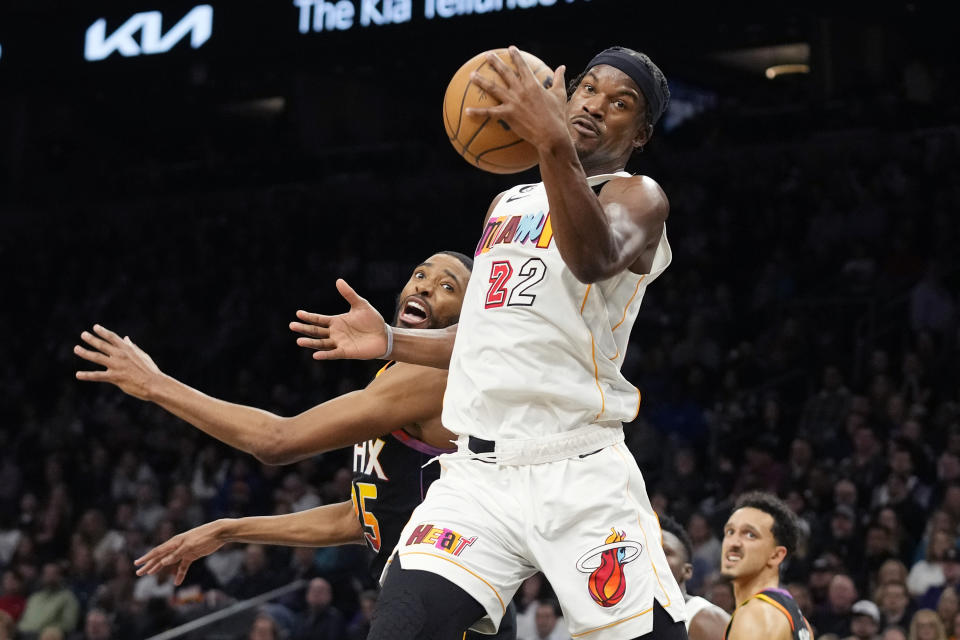 Miami Heat forward Jimmy Butler (22) grabs a rebound in front of Phoenix Suns forward Mikal Bridges, left, as Suns guard Landry Shamet, right, looks on during the first half of an NBA basketball game in Phoenix, Friday, Jan. 6, 2023. (AP Photo/Ross D. Franklin)