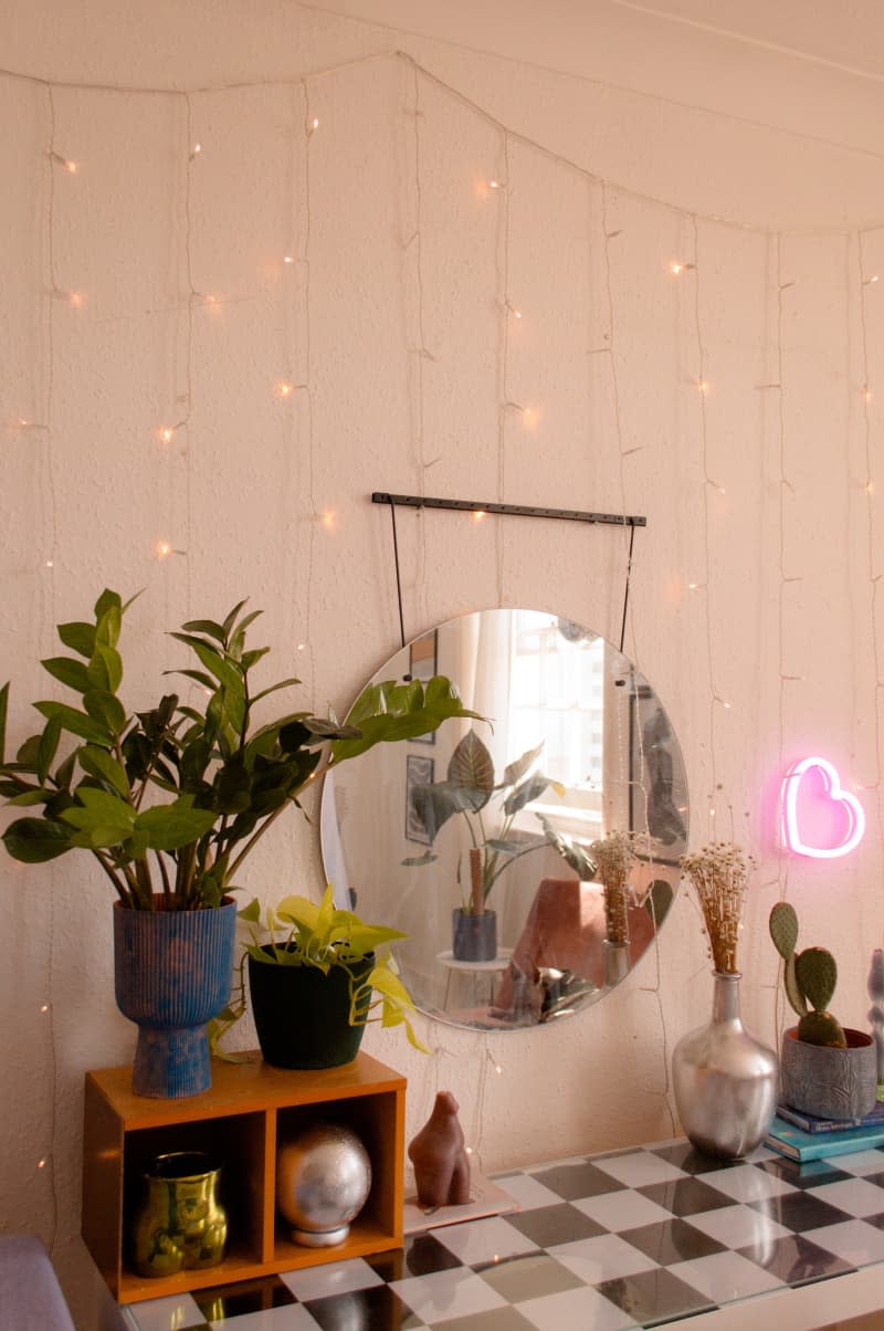 A large circular mirror hangs next to a string of lights.