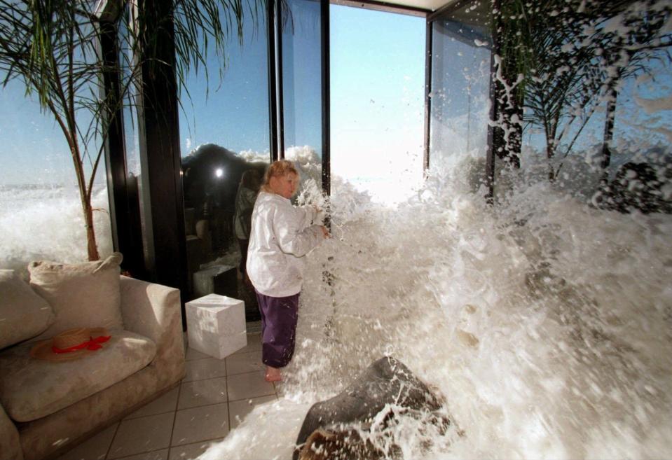 Marilyn Lane attempts to close her doors to prevent a large wave from crashing into the living room of her home near Ventura, Calif., in this Jan. 30, 1998, file photo.  In 1997-98, several storms fueled by a strong El Nino slammed into California, killing 17 and causing an estimated $550 million in damaged crops and property.