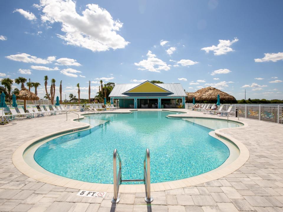 A pool with lounge chairs surrounding it.