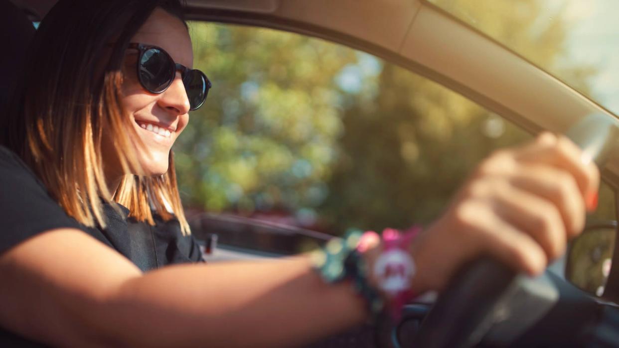 Smiling young woman driving a car.