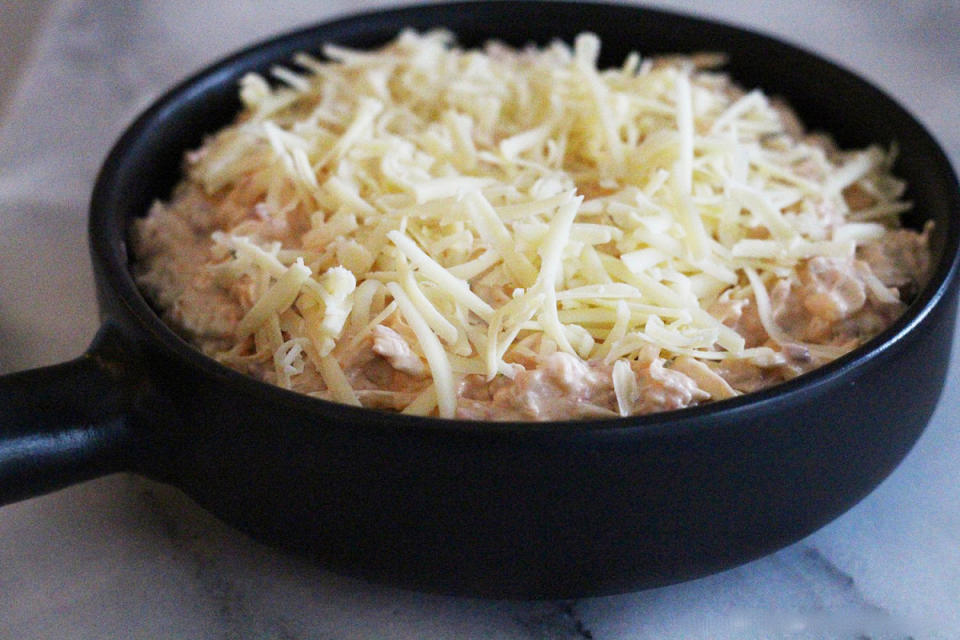 <p>Spread the dip into the baking dish and top with the remaining cheese.</p>