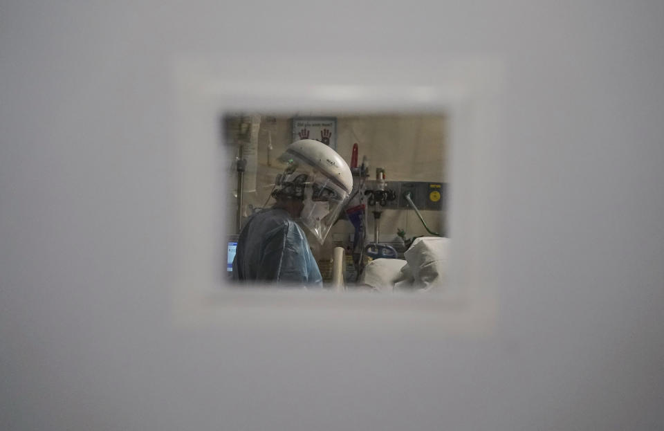 FILE - A nurse tending to a COVID-19 patient, is seen through a small window in an intensive care unit ,at Mission Hospital in Mission Viejo, Calif., on Dec. 21, 2020. Many American hospitals are looking broad for health care workers, saying they're facing a dire shortage of nurses amid the slogging pandemic. It could be just in time as there's an unusually high number of green cards available this year for foreign professionals seeking to move to the United States. (AP Photo/Jae C. Hong, File)