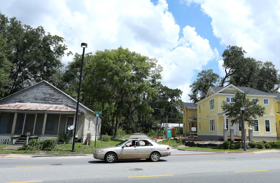 A motorist drives past the intersection of Southwest Fifth Terrace and Depot Avenue, a corner that features new construction of multi-family housing on one side of the street and an existing home on the left.