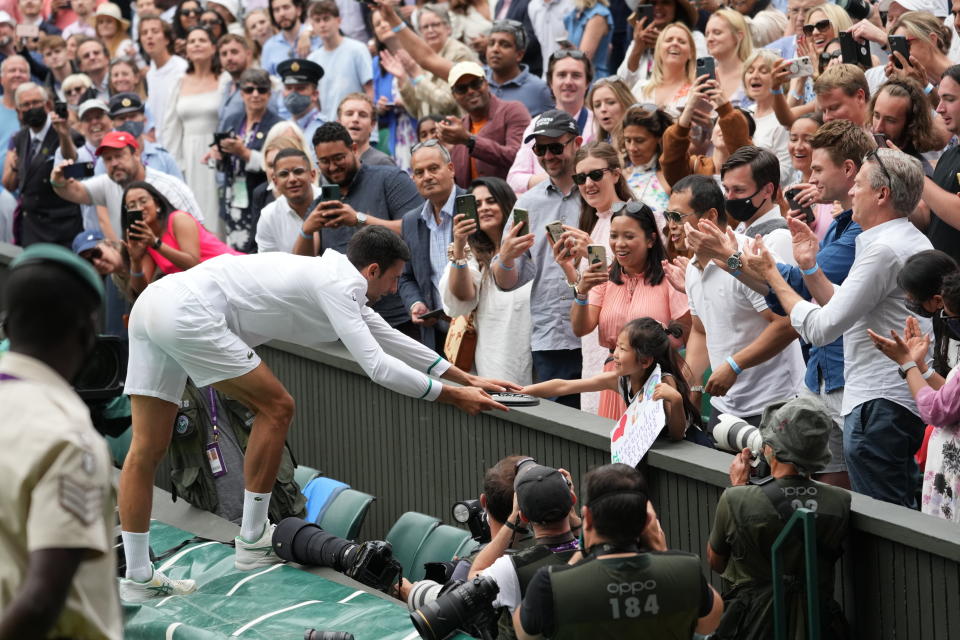 Novak Djokovic obsequia su raqueta a una jovencita tras ganar la final del torneo de Wimbledon ante Matteo Berrettini, el domingo 11 de juliod e 2021, en Londres. (AP Foto/Alberto Pezzali)