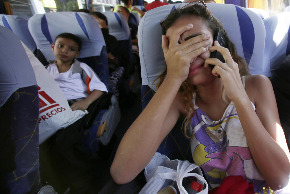 In this Sept. 5, 2018 photo, a Venezuelan migrant cries as she talks to her father on the phone, who is staying in Ecuador, as she boards a bus that will take her to the airport to fly back to her homeland, in Quito, Ecuador. The woman will travel back home with a group of migrants in an airplane provided by the government of Venezuela. (AP Photo/Dolores Ochoa)