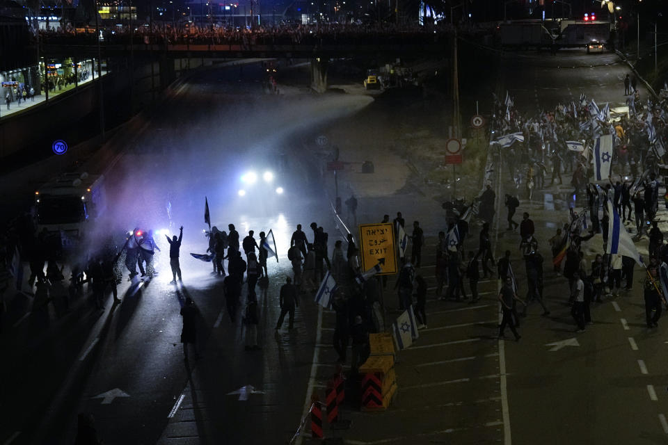 Israeli police use a water cannon to disperse Israelis blocking a highway during a protest against plans by Prime Minister Benjamin Netanyahu's government to overhaul the judicial system in Tel Aviv, Israel, Saturday, March 25, 2023. (AP Photo/Ariel Schalit)