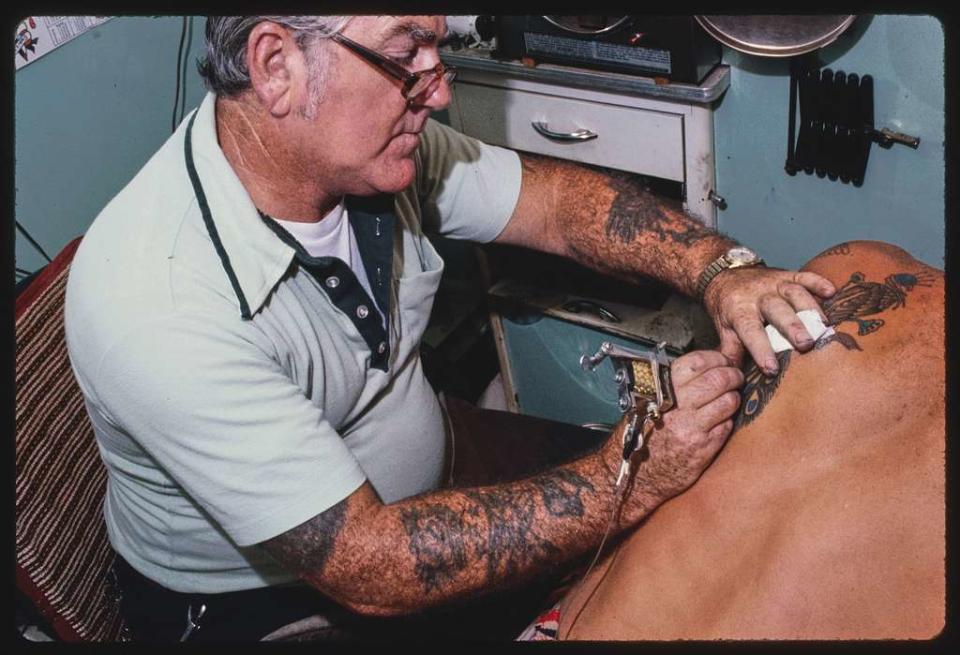 Buddy Mott tattoos a person's back in a photo published in 1979.