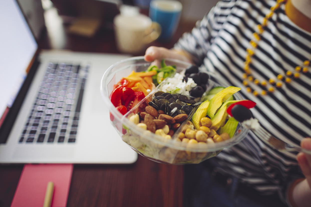 Woman eating a healthy snack while working from home. (Getty Images)