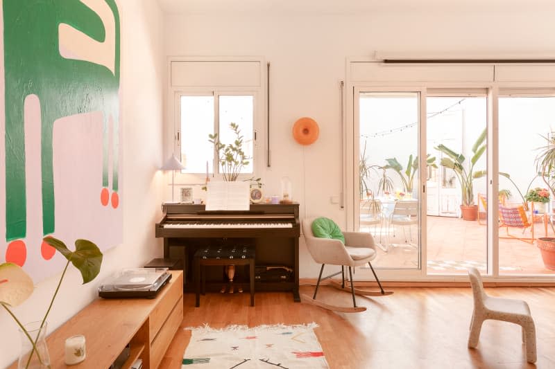 white living room with piano, large windows, and white and wood accents