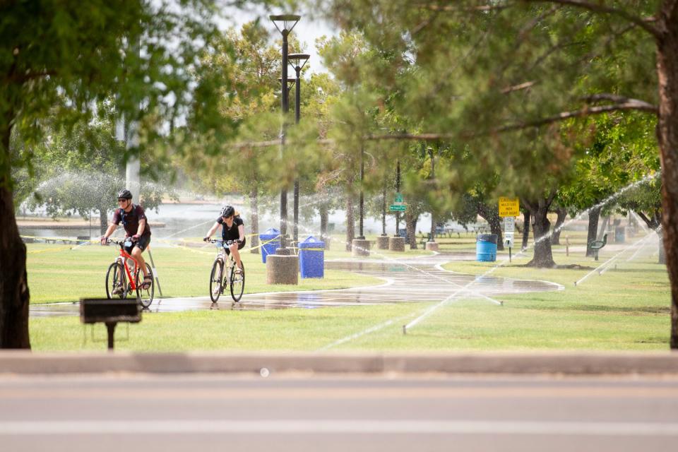 Bicyclists enjoy a ride through sprinklers at Chaparral Park in Scottsdale on July 13, 2020. The temperature for the day was expected to reach a high of 112 degrees Fahrenheit.