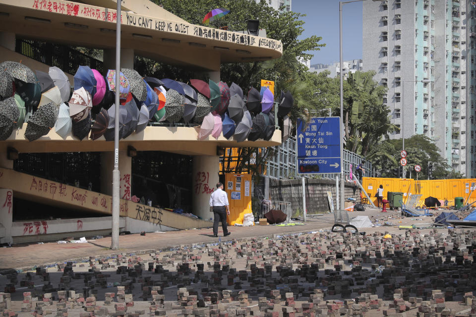 A man walks past barricades built by protesters at Hong Kong Baptist University in Hong Kong, Friday, Nov. 15, 2019. Protesters who have barricaded themselves in a Hong Kong university partially cleared a road they were blocking and demanded that the government commit to holding local elections on Nov. 24. (AP Photo/Kin Cheung)