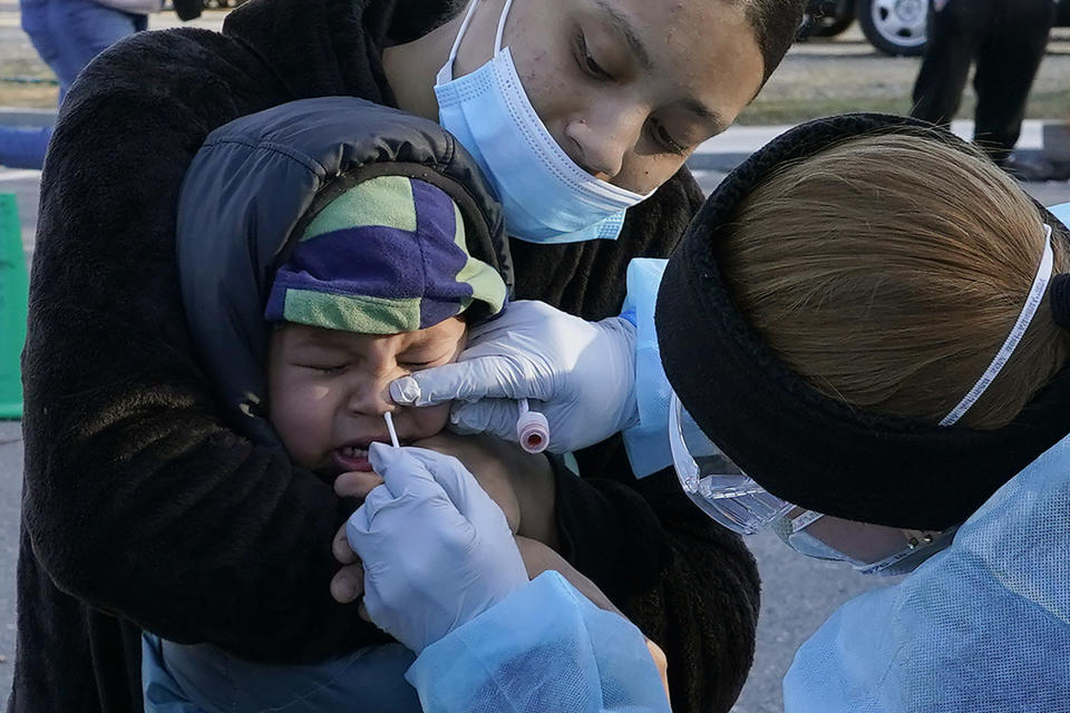 Jamillette Gomes holds her two-year-old son, Avian, as he receives a COVID-19 test, Thursday, Dec. 3, 2020, in Lawrence, Mass. (AP Photo/Elise Amendola)