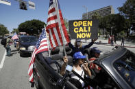 Protesters drive by in a convertible car during a rally calling for an end to California Gov. Gavin Newsom's stay-at-home orders amid the COVID-19 pandemic, Wednesday, April 22, 2020, outside of City Hall in downtown Los Angeles. (AP Photo/Marcio Jose Sanchez)