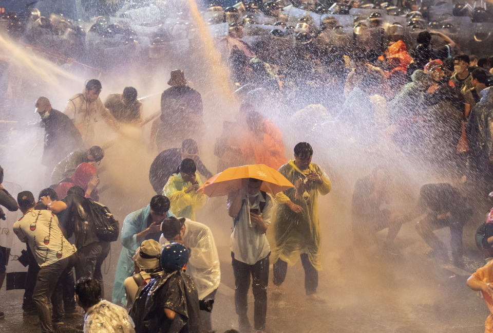 Pro democracy demonstrators face water canons as police try to clear the protest venue in Bangkok, Thailand, Friday, Oct. 16, 2020. Thailand prime minister has rejected calls for his resignation as his government steps up efforts to stop student-led protesters from rallying in the capital for a second day in defiance of a strict state of emergency. (AP Photo/Gemunu Amarasinghe)