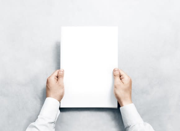 A person holds a blank piece of paper.