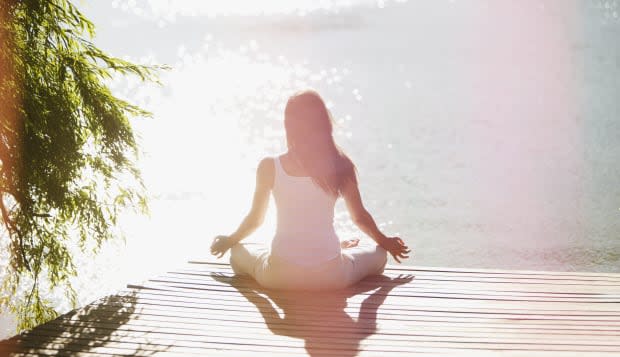 Woman practicing yoga on pier