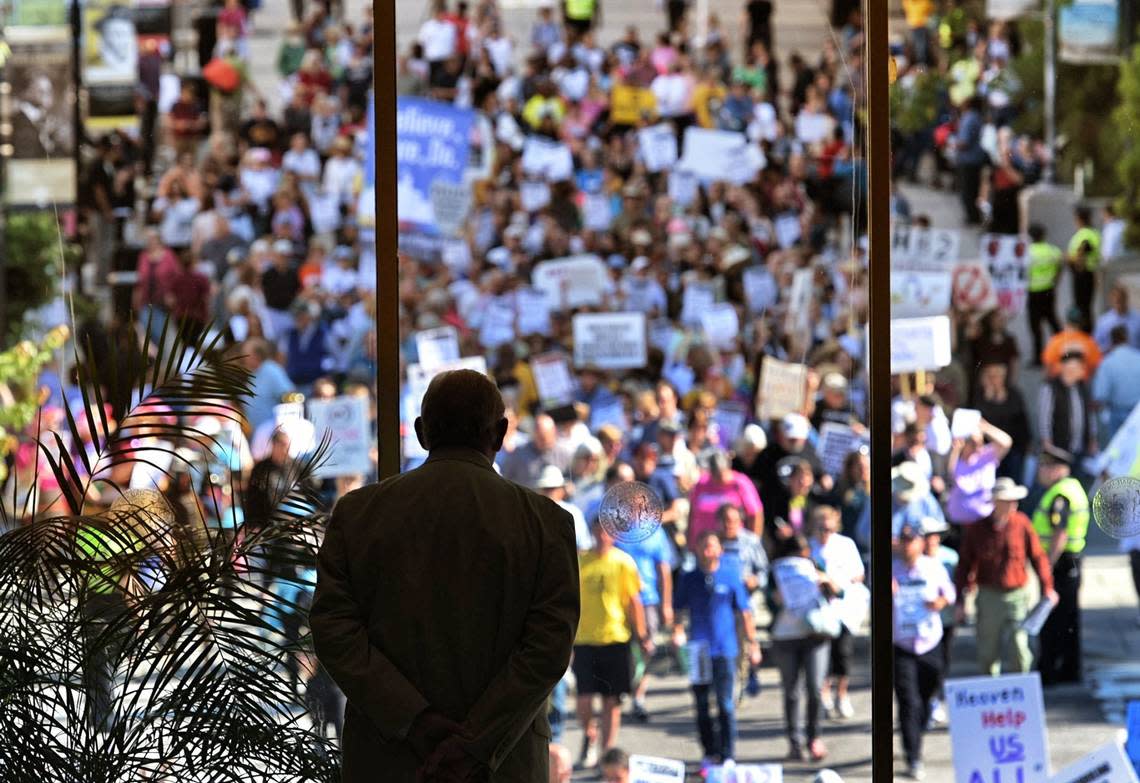 A member of the N.C. General Assembly Sgt. at Arms watches as members of the Moral Monday cross the street towards the legislative building Monday, May 16, 2016. Hundreds of protesters convened on the General Assembly to protest controversial HB2.