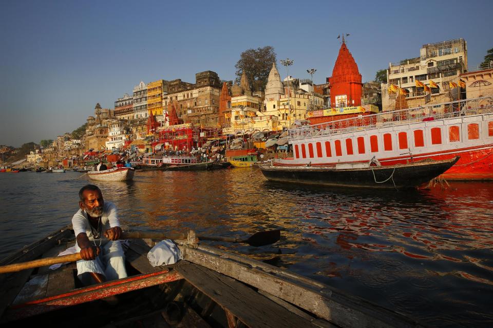 In this Tuesday, April 1, 2014, photo, an Indian boatman rows past his various Ghats on the banks of the river Ganges, in Varanasi, India. For tens of millions of people, the city of Varanasi, on the banks of the river Ganges, is a place of pilgrimage, where devout Hindus believe they earn instant salvation. But in recent weeks Varanasi also has become the noisy battleground for India's most-watched contest in its national elections: Two of the country’s most prominent politicians are facing off in a contest for the city’s sole parliamentary seat. (AP Photo /Manish Swarup)