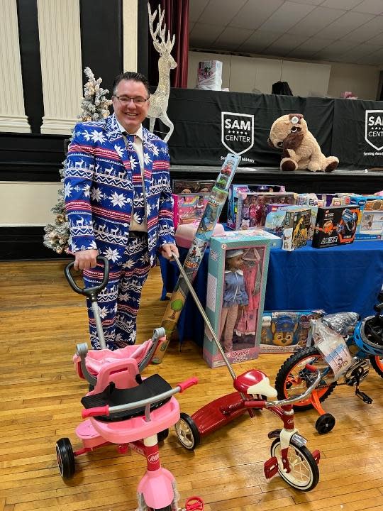 Bryan Bowman, founder of the Serving Area Military (SAM) Center, is pictured with dozens of toys to be given out this week to local military families.