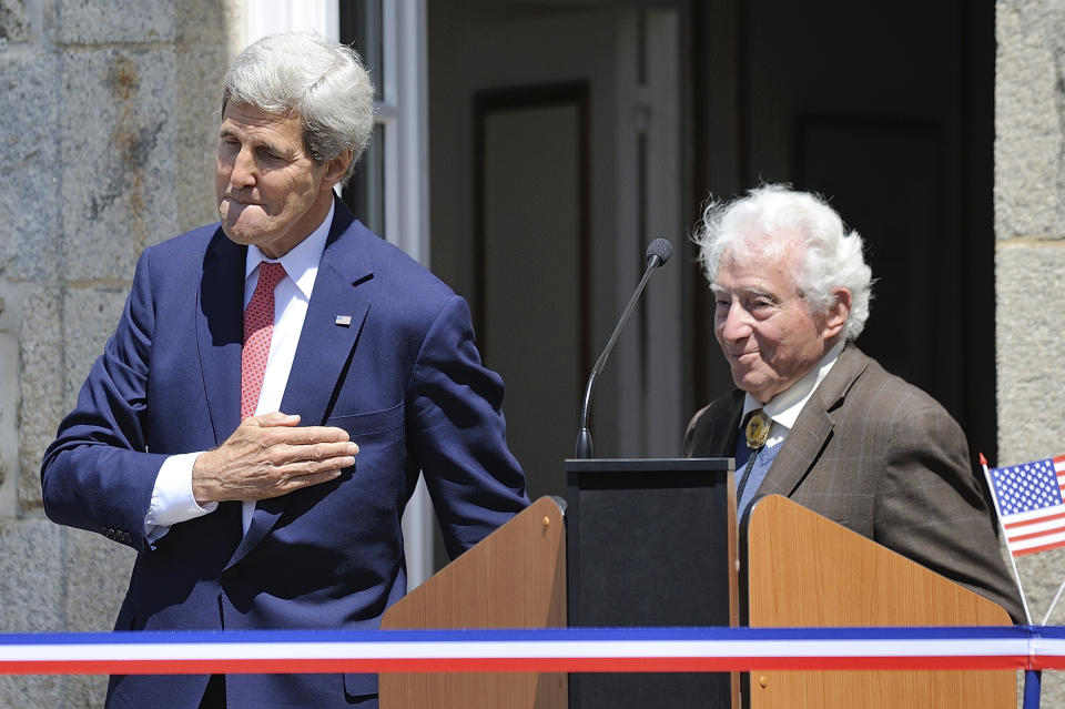 FILE - In this Saturday, June 7, 2014 file photo US Secretary of State John Kerry and World War II photographer Tony Vaccaro, right, attend the inauguration of the Tony Vaccaro Square, in front of the Saint-Briac-sur-Mer city hall, western France. Vaccaro, 97, was thrown into WWII with the 83rd Infantry division which fought, like Charles Shay, in Normandy, and then came to Schmetz's doorstep for the Battle of the Bulge. On top of his military gear, he also carried a camera, and became a fashion and celebrity photographer after the war. COVID-19 caught up with him last month. Like everything bad life threw at him, he shook it off, attributing his survival to plain "fortune." (AP Photo/ Jean Sebastien Evrard, Pool)