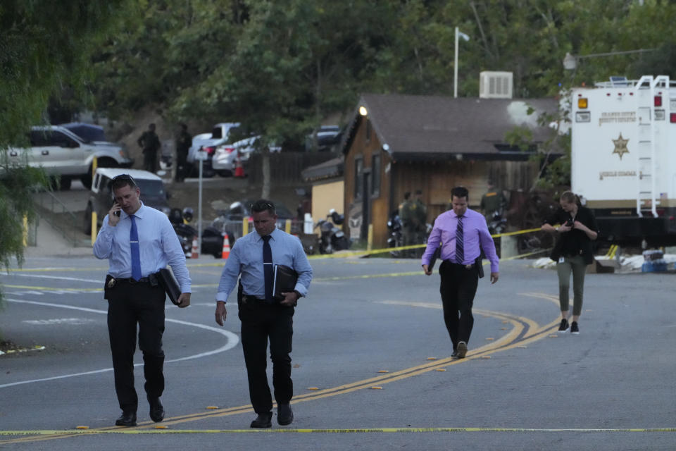 Detectives walk at the scene of a mass shooting at Cook's Corner, Thursday, Aug. 24, 2023, in Trabuco Canyon, Calif. (AP Photo/Damian Dovarganes)