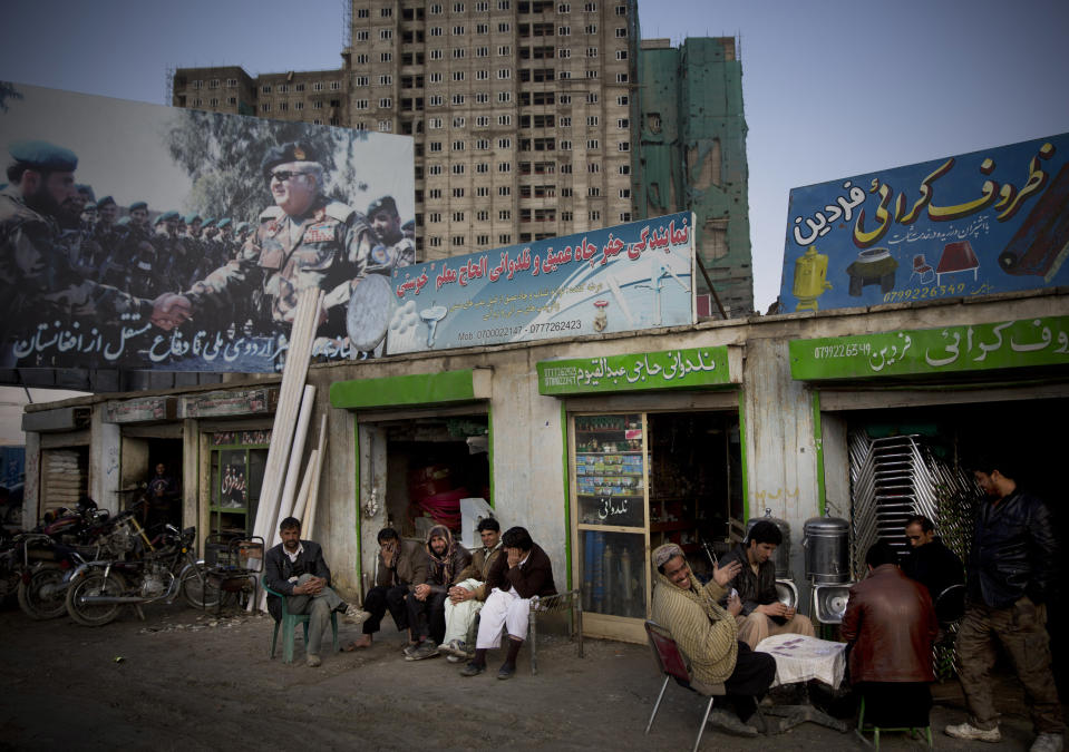 In this Monday, March 17, 2014 photo, Afghan men play cards under a huge election poster showing Abdul Rahim Wardak, Afghanistan’s former defense minister, shaking hands with soldiers in Kabul, Afghanistan. Wardak pulled out of the presidential elections, but warlords with a violent past have played a role in influencing Afghan politics since a U.S.-led coalition helped oust the Taliban in 2001. But they are emerging to play an overt political role in next month’s presidential elections as President Hamid Karzai leaves the scene. (AP Photo/Anja Niedringhaus)