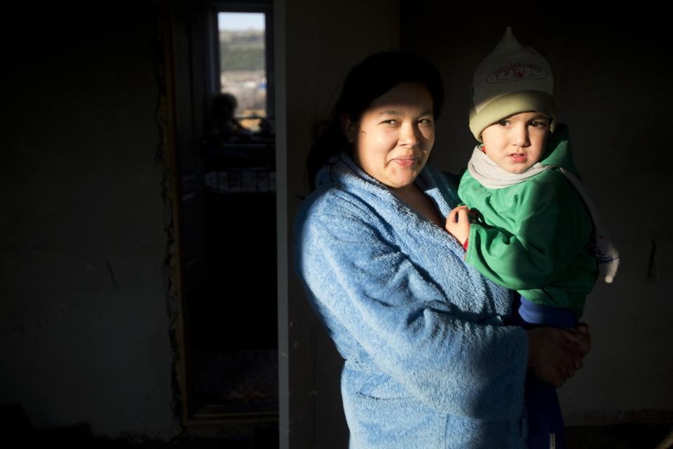 In this photo taken Thursday March 27, 2014 Crimea's Tatar Liliya Resulova, 24, holds her son, Emir, 2, inside of their building at recent squatter settlement in Lozovoye-2, not far from Simferopol, Crimea. On Saturday the Crimean Tatar Qurultay, a religious congress will determine whether the Tatars will accept Russian citizenship and the political system that comes with it, or remain Ukrainian citizens on Russian soil. (AP Photo/Pavel Golovkin)
