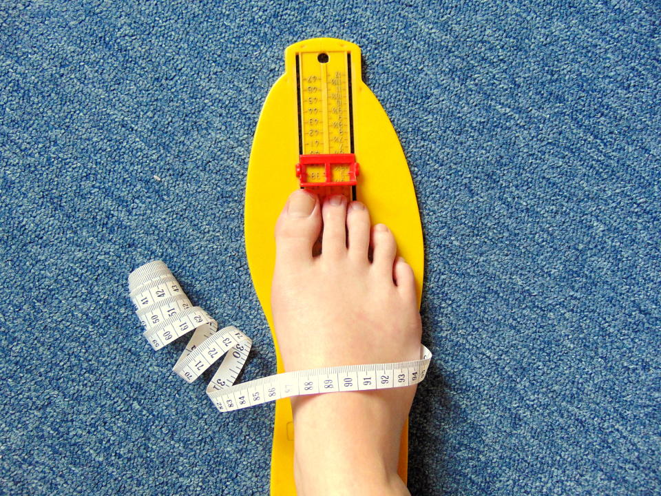 A woman's feet being measured. 