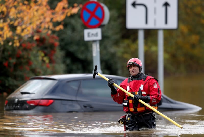 An emergency service worker stands at a flooded road in central Rotherham, near Sheffield