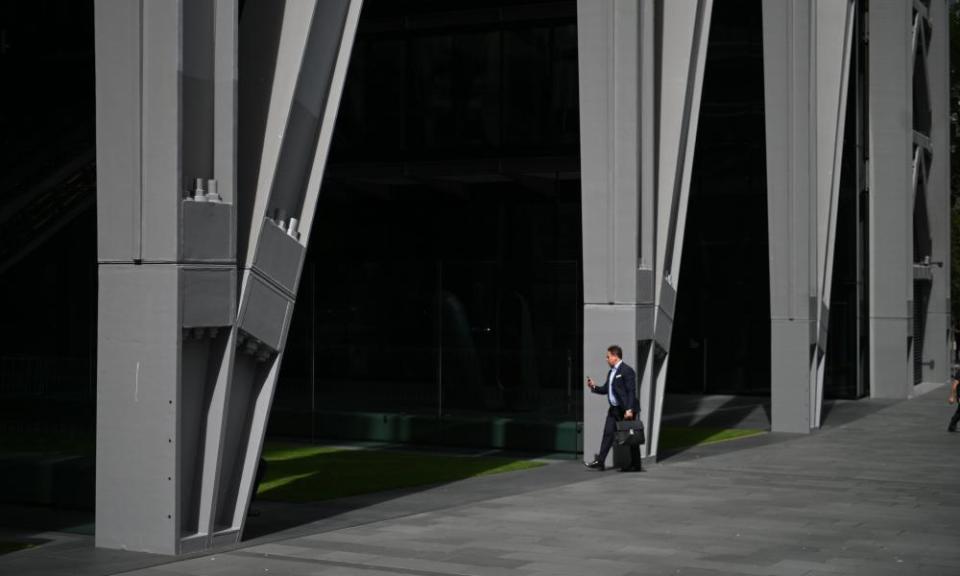 A man arrives at an office block in the City, a square mile in the heart of London traditionally home of the finance industry, in August.