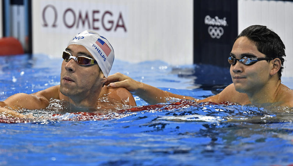 FILE - United States' Michael Phelps and Singapore's Joseph Schooling check their times after a men's 100-meter butterfly heat during the swimming competitions at the 2016 Summer Olympics, Thursday, Aug. 11, 2016, in Rio de Janeiro, Brazil. Olympic gold medal swimmer Joseph Schooling has apologized for using cannabis in Vietnam while competing there on leave from military service in his native Singapore. Schooling achieved superstar status in Singapore when he won his country’s first and only Olympic title at the 2016 Rio de Janeiro Games. He won the 100 meters butterfly beating Michael Phelps in the American great’s last Olympic race. (AP Photo/Martin Meissner, File)