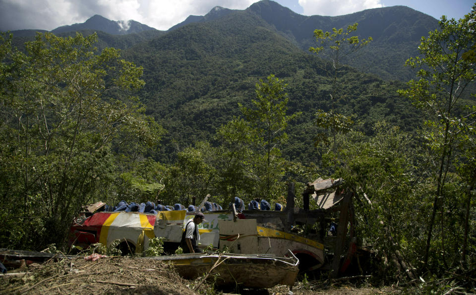 Un guardaparques camina en medio de los restos de un autobús que chocó de frente con otro vehículo y se precipitó a un barranco en Yolosa, Bolivia, el lunes 22 de abril de 2019. (AP Foto / Juan Karita)