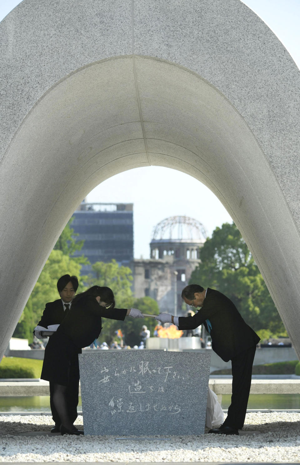 Hiroshima Mayor Kazumi Matsui, right, dedicates the list of the victims of atomic bombing to the cenotaph during a ceremony to mark the 73rd anniversary of the bombing at Hiroshima Peace Memorial Park in Hiroshima, western Japan, Monday, Aug. 6, 2018. Matsui raised concerns in his peace address about the rise of egocentric policies in the world and warned against the idea of nuclear deterrence as a threat to global security. The Atomic Bomb Dome is seen in the background. (Yohei Nishimura/Kyodo News via AP)
