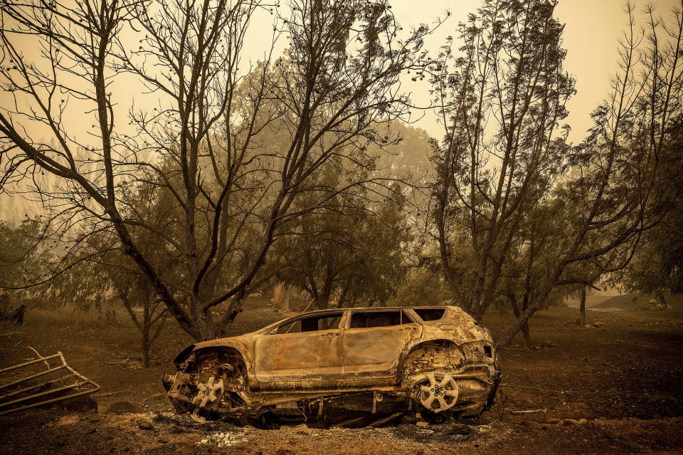 A scorched vehicle rests sits next to a driveway as the McKinney Fire burns in Klamath National Forest, Calif., on Sunday, July 31, 2022. (AP Photo/Noah Berger)